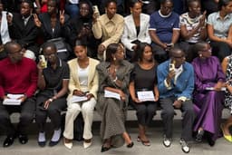 A packed front row photographing a runway show