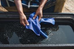 Hands working indigo dye into patterned adire cloth